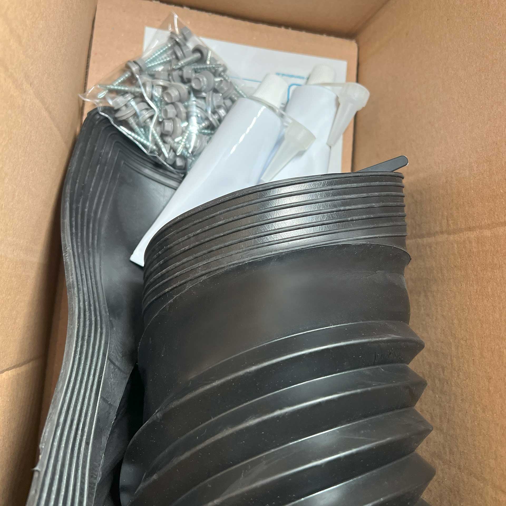Rohrmanschette Retrofit eingerollt in der Verpackung samt Inhalt: Schrauben und Dcihtungsmasse für die Montage im Karton fotografiert.